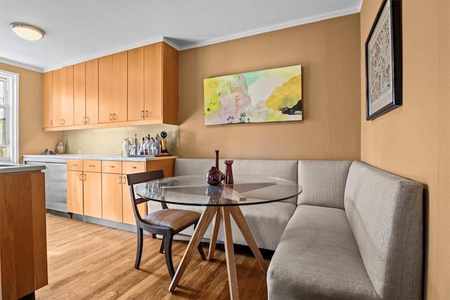 dining area with breakfast area, light hardwood / wood-style floors, and ornamental molding