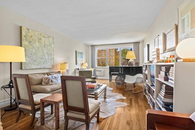 sitting room with a wall mounted air conditioner and hardwood / wood-style floors