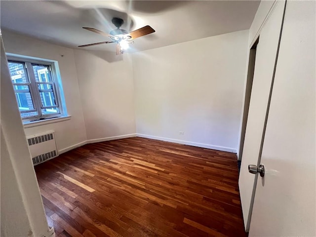 spare room with ceiling fan, radiator heating unit, and dark wood-type flooring