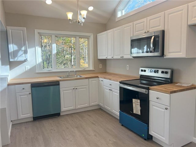 kitchen with butcher block countertops, lofted ceiling, white cabinetry, and stainless steel appliances