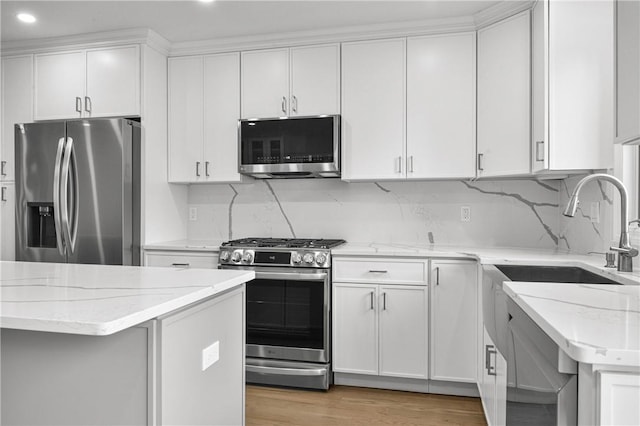 kitchen featuring white cabinets, light hardwood / wood-style floors, light stone counters, and appliances with stainless steel finishes