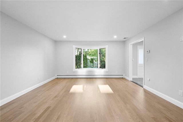 empty room with a baseboard radiator and light hardwood / wood-style floors