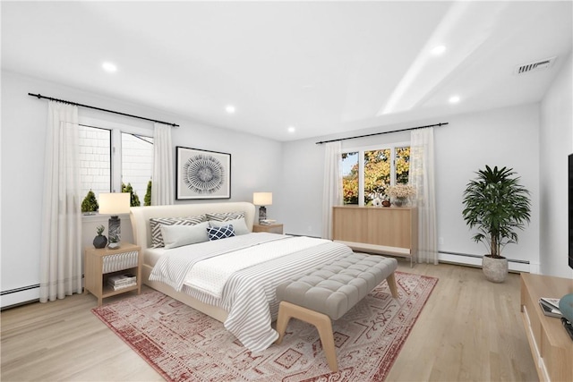 bedroom featuring light wood-type flooring and a baseboard heating unit