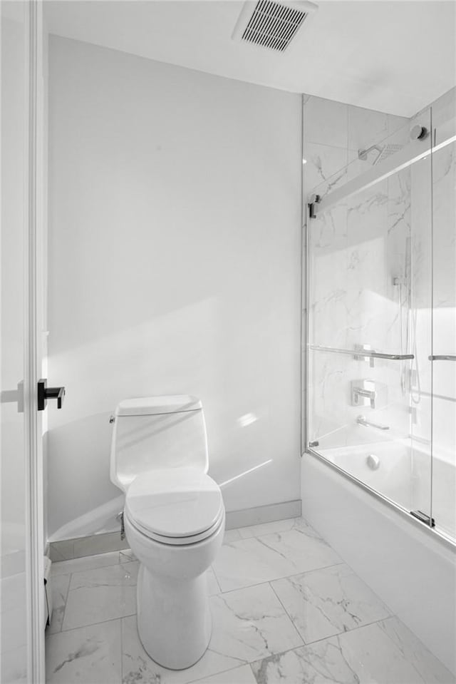 bathroom featuring toilet and bath / shower combo with glass door