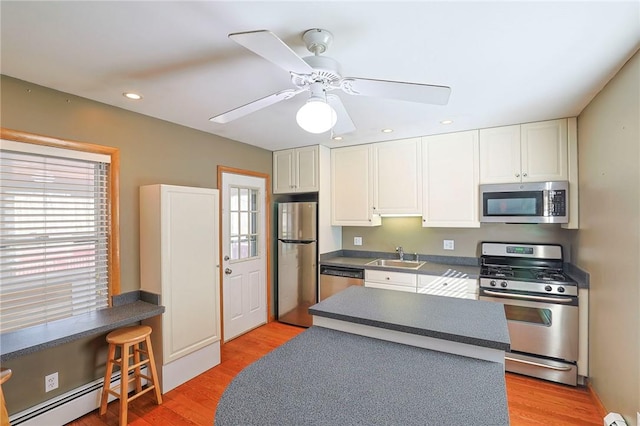 kitchen with hardwood / wood-style floors, stainless steel appliances, a baseboard heating unit, and sink