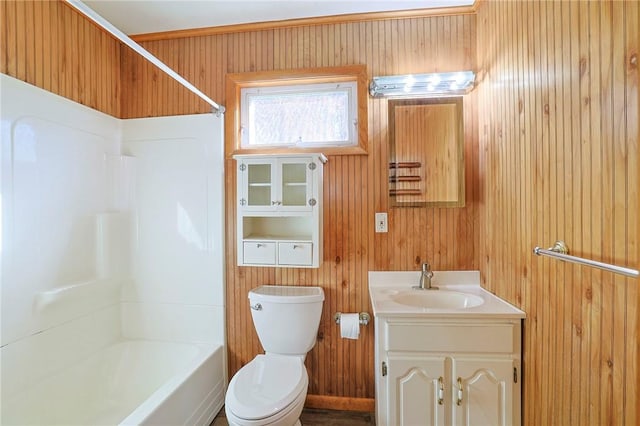 full bathroom with wooden walls, vanity, tub / shower combination, and toilet