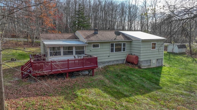 rear view of property featuring a lawn, a sunroom, and a deck
