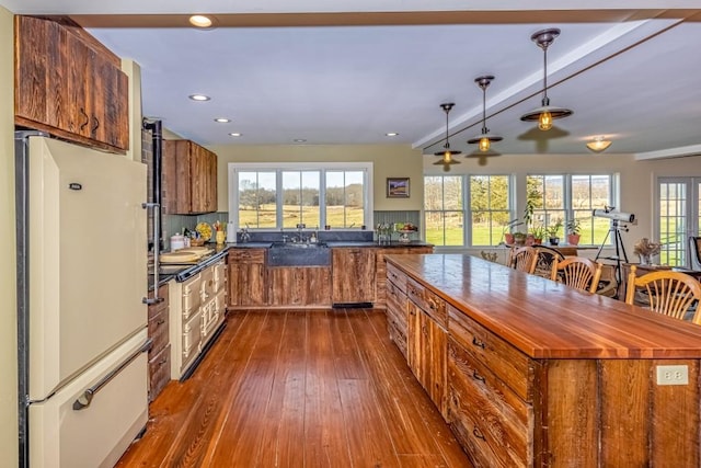 kitchen featuring beamed ceiling, a healthy amount of sunlight, dark hardwood / wood-style floors, and white refrigerator