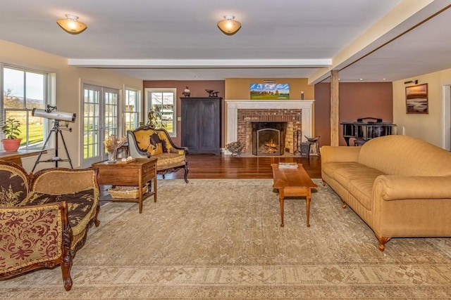 living room with hardwood / wood-style flooring, a fireplace, a wealth of natural light, and beamed ceiling