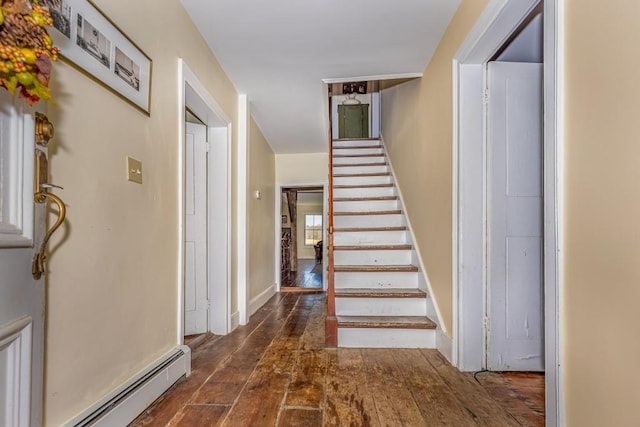 stairs featuring wood-type flooring and a baseboard heating unit