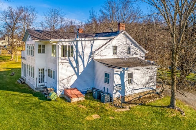 rear view of property with a lawn and central air condition unit