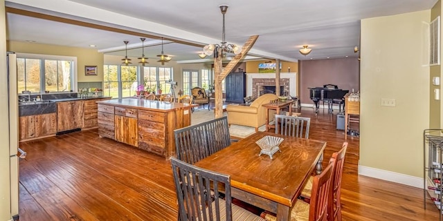 dining area featuring a fireplace, beam ceiling, and dark hardwood / wood-style floors