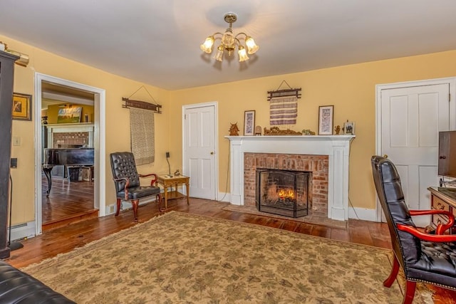 living room with a chandelier, hardwood / wood-style flooring, a brick fireplace, and a baseboard radiator