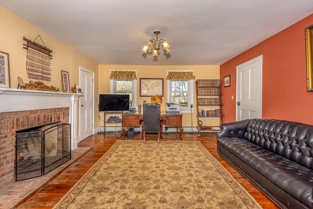 living room with hardwood / wood-style floors, a chandelier, and a brick fireplace