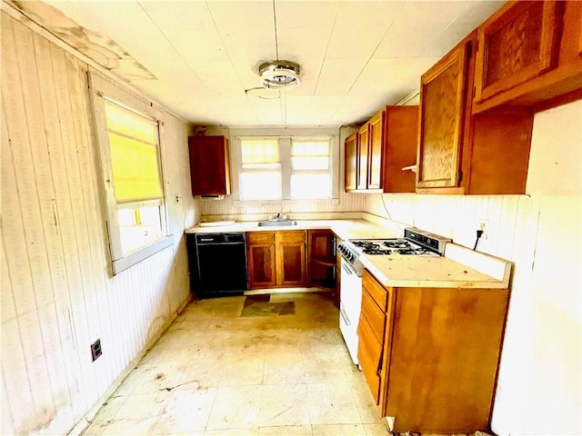 kitchen featuring sink, black dishwasher, wooden walls, and gas range gas stove