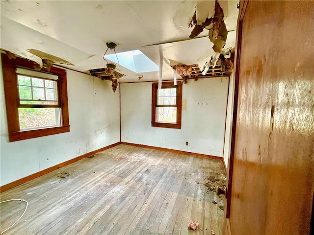 spare room featuring wood-type flooring and a skylight