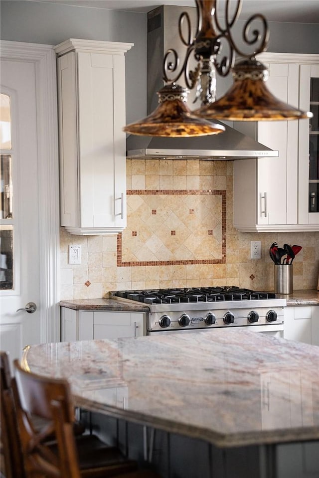 kitchen featuring decorative backsplash, custom range hood, stainless steel range, light stone counters, and white cabinetry