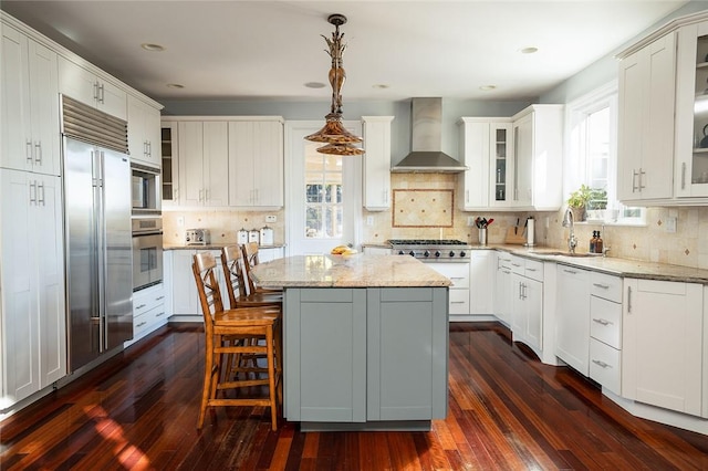 kitchen with dark hardwood / wood-style flooring, sink, wall chimney range hood, decorative light fixtures, and a center island