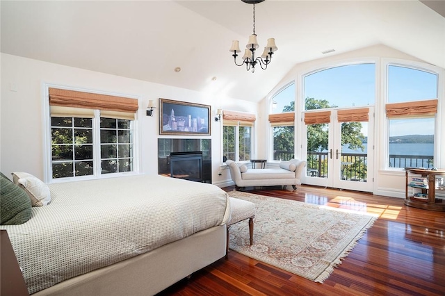 bedroom with dark hardwood / wood-style floors, a chandelier, lofted ceiling, access to outside, and a water view