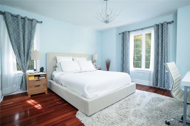 bedroom with dark hardwood / wood-style flooring and an inviting chandelier