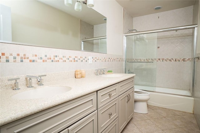 full bathroom featuring tile patterned flooring, toilet, shower / bath combination with glass door, vanity, and tile walls