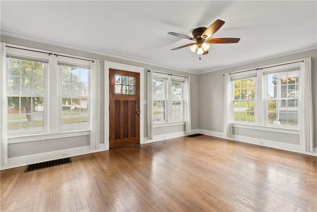 interior space with hardwood / wood-style flooring, ceiling fan, ornamental molding, and a wealth of natural light