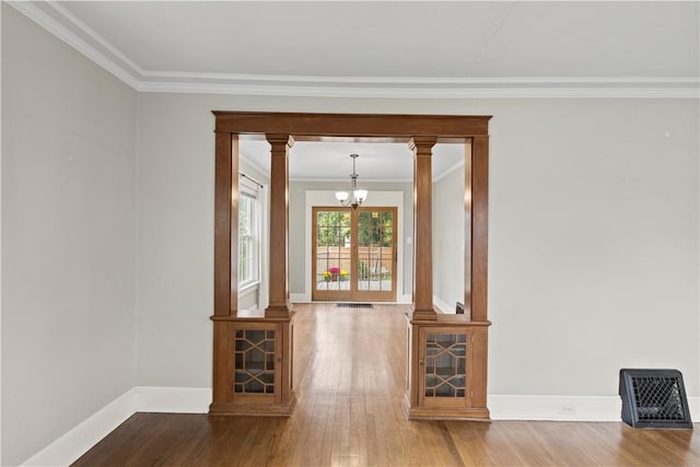 unfurnished living room featuring an inviting chandelier, wood-type flooring, and ornamental molding