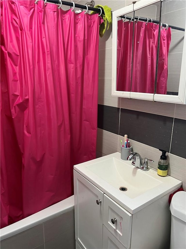 full bathroom with shower / bath combo, vanity, toilet, and backsplash