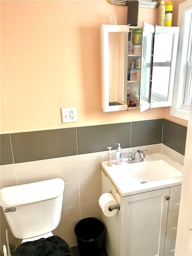 bathroom with vanity, tile walls, and toilet