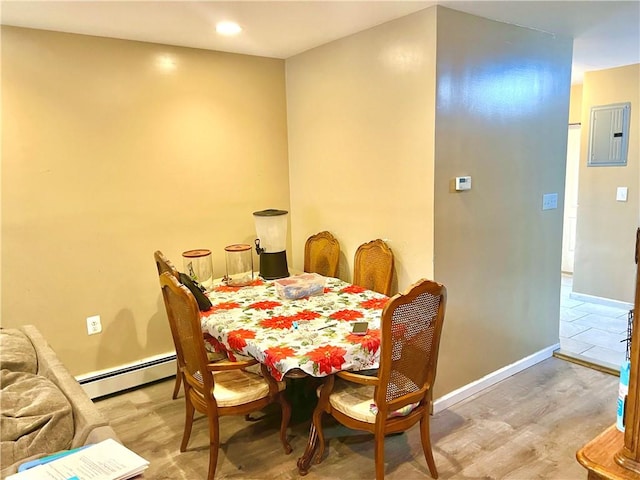 dining area featuring electric panel, a baseboard radiator, and light wood-type flooring