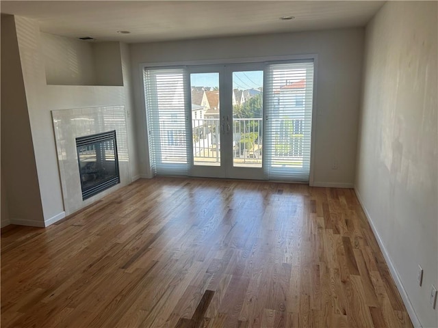 unfurnished living room featuring hardwood / wood-style flooring and a tile fireplace