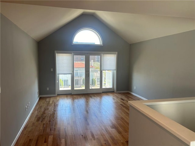 empty room with hardwood / wood-style flooring and vaulted ceiling