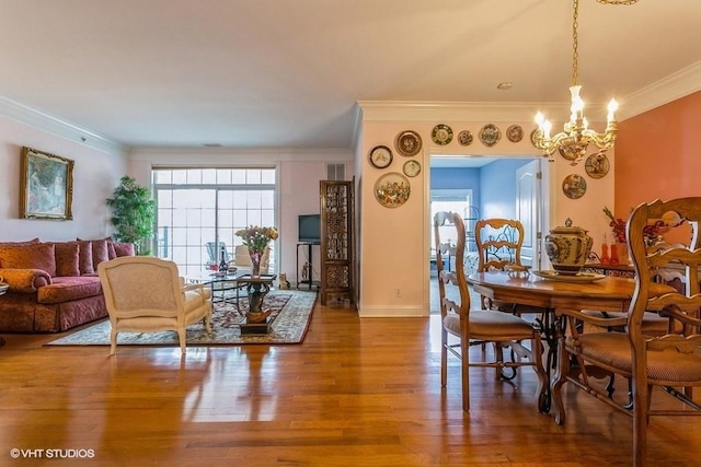 dining room with plenty of natural light, wood-type flooring, ornamental molding, and an inviting chandelier