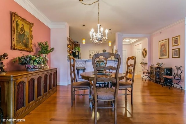 dining area featuring crown molding, wood-type flooring, and an inviting chandelier