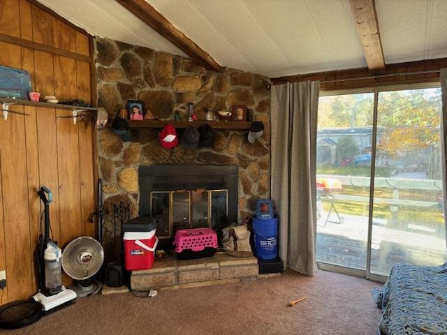 carpeted living room featuring vaulted ceiling with beams, a fireplace, and wooden walls