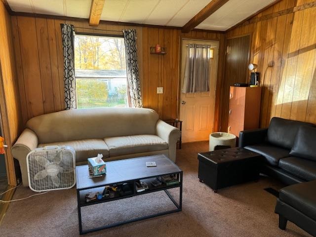 carpeted living room featuring vaulted ceiling with beams and wooden walls