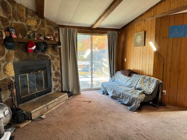 living area with carpet, wood walls, and a stone fireplace