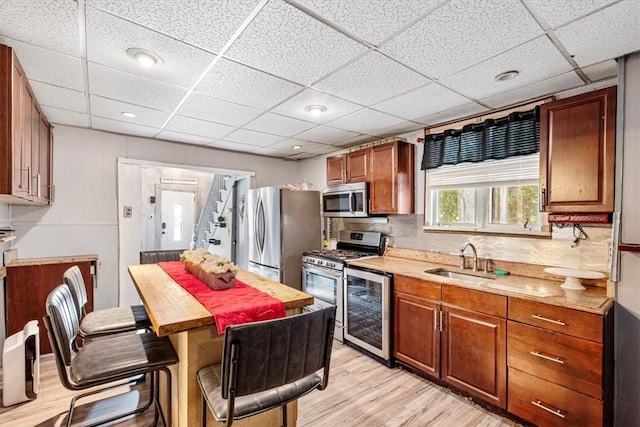 kitchen featuring a drop ceiling, sink, light wood-type flooring, and stainless steel appliances