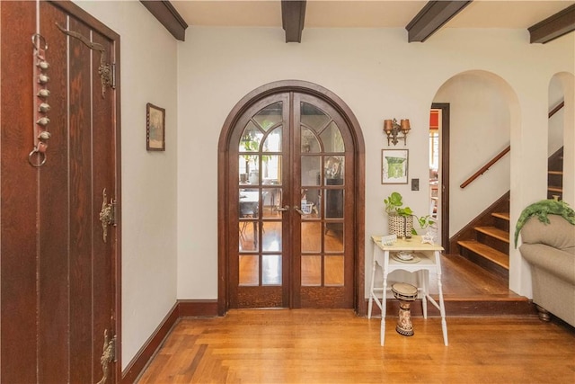 entrance foyer with beam ceiling, french doors, and wood-type flooring