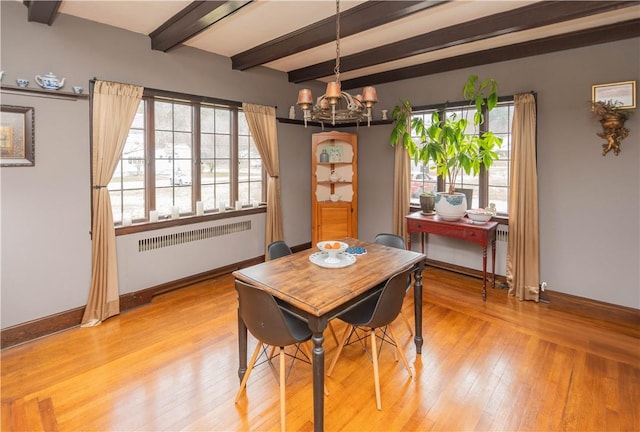 dining room with beam ceiling, radiator, a chandelier, and light hardwood / wood-style floors