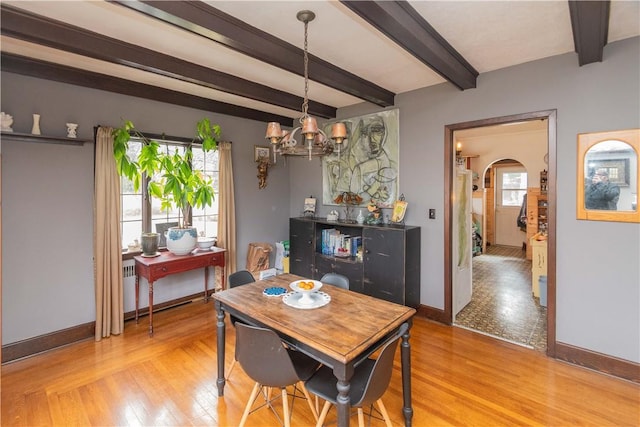 dining space with plenty of natural light, beam ceiling, an inviting chandelier, and light hardwood / wood-style flooring