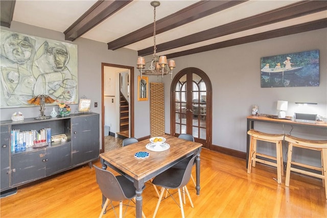 dining area with hardwood / wood-style flooring, french doors, beamed ceiling, and an inviting chandelier