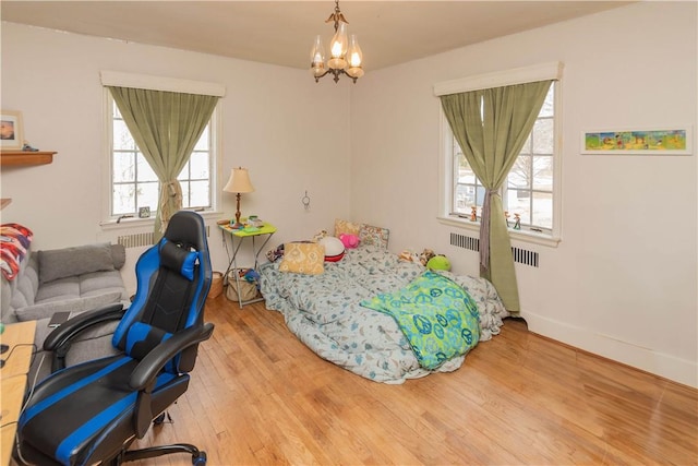 bedroom with a notable chandelier, light hardwood / wood-style floors, and radiator heating unit