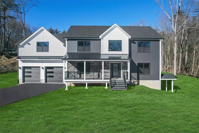 view of front of home featuring covered porch, a garage, and a front lawn