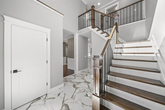 staircase featuring decorative columns and a high ceiling