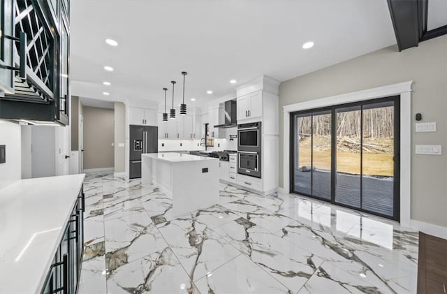 kitchen with wall chimney range hood, a kitchen island, pendant lighting, white cabinets, and appliances with stainless steel finishes