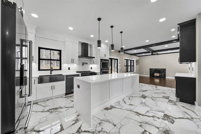 kitchen featuring stainless steel dishwasher, wall chimney exhaust hood, sink, a center island, and white cabinetry