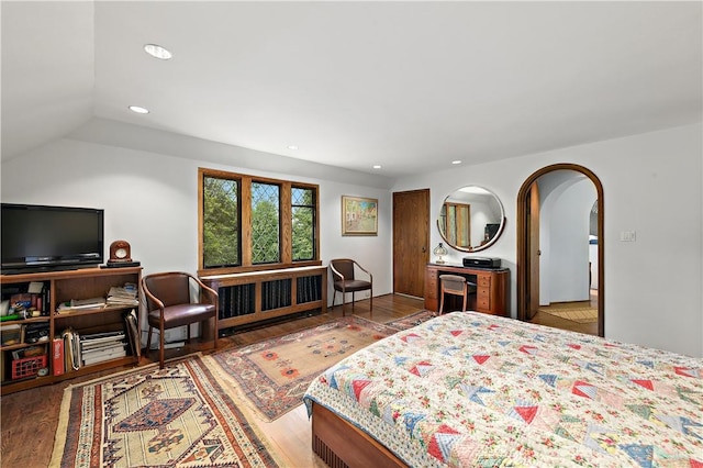 bedroom featuring arched walkways, recessed lighting, lofted ceiling, and wood finished floors