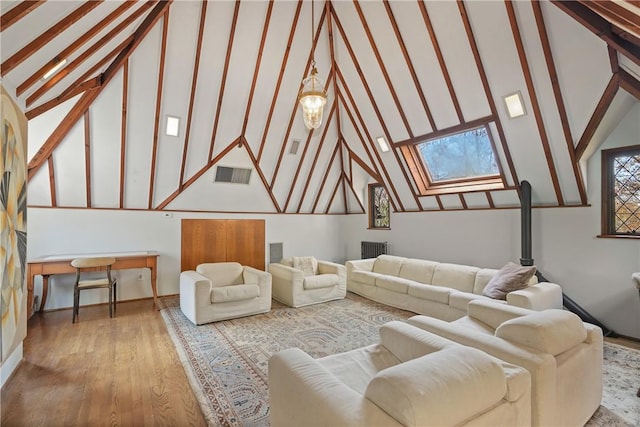 living area with high vaulted ceiling, a skylight, wood finished floors, visible vents, and radiator heating unit