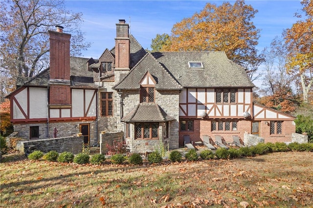 back of property featuring stone siding, a lawn, and stucco siding